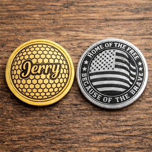 Two coins, one gold with 'Jerry' engraving and the other silver with American flag design, on a wooden surface.
