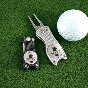 Two golf divots with 'BETTY' branding on a green surface with a golf ball.