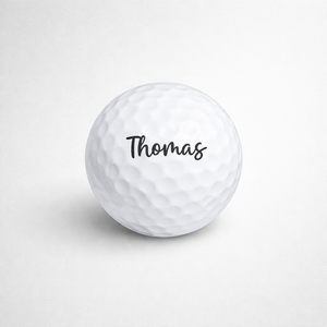 White golf ball with 'Thomas' printed on a light gray background