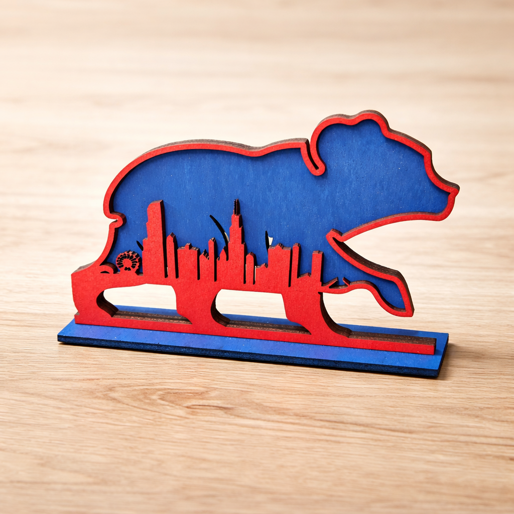 Blue and red bear-shaped object with city skyline design on a wooden surface