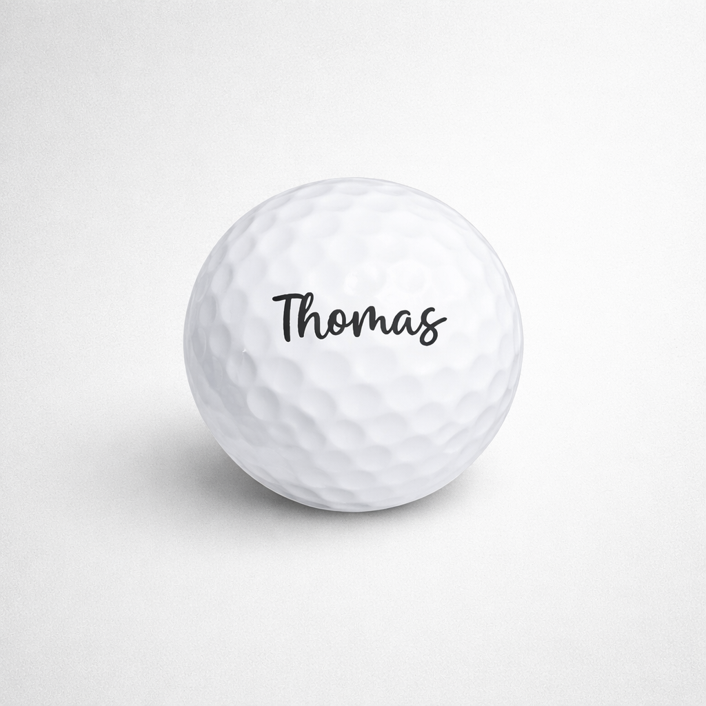 White golf ball with 'Thomas' printed on a light gray background